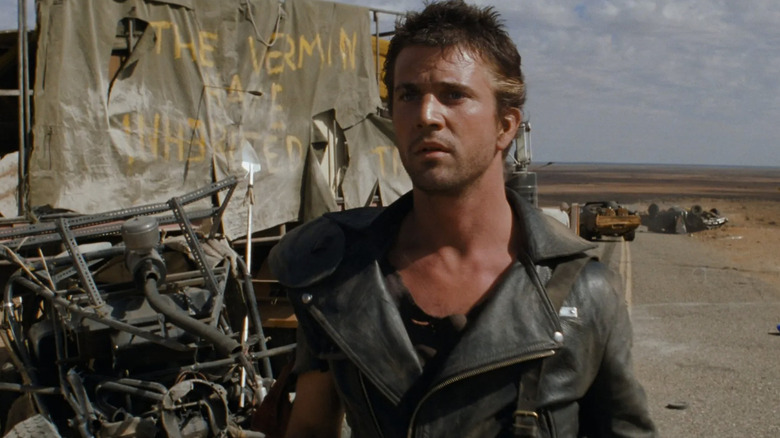 Max Rockatansky (Mel Gibson) stands by a wrecked vehicle in Mad Max 2