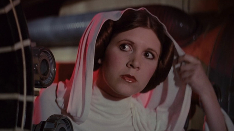 Leia Organa (Carrie Fisher) peers around a corner while lifting her veil in Star Wars
