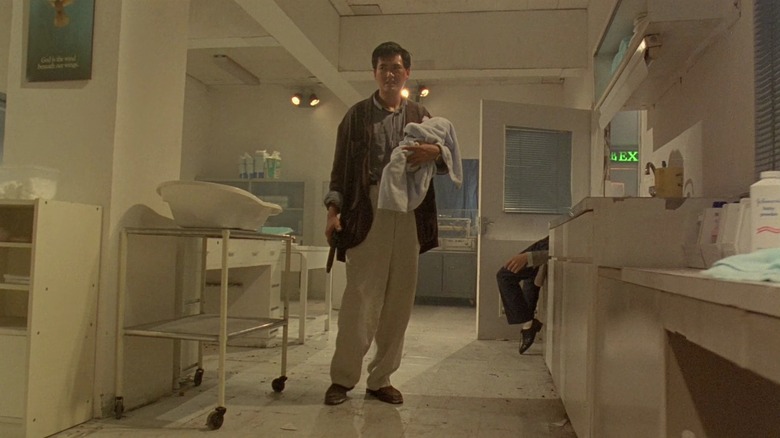 Chow Yun-fat as Inspector "Tequila" Yuen Ho-yan in Hard Boiled, armed and holding a baby in a hospital room.