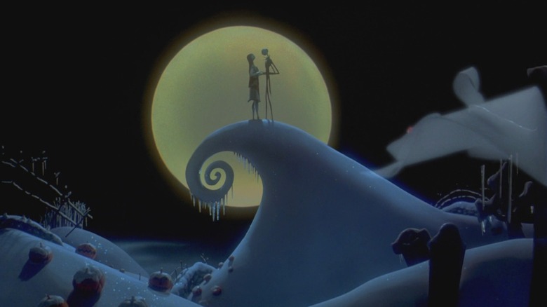 Chris Sarandon/Danny Elfman as Jack Skellington and Catherine O'Hara as Sally in The Nightmare Before Christmas, the pair facing each other atop a curling snowy peak in front of the big, bright moon.