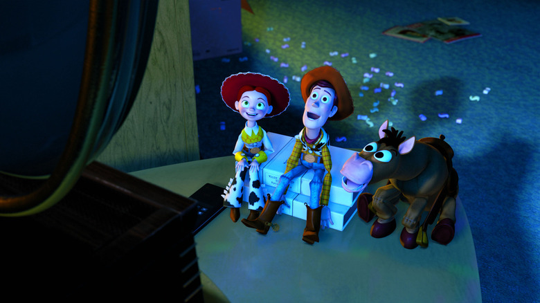 Tom Hanks as Woody and Joan Cusack as Jessie sitting with Bullseye as they gleefully watch a television.