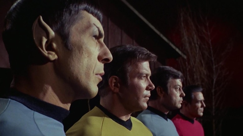 Spock (Leonard Nimoy), Kirk (William Shatner), McCoy (DeForest Kelley), and Scotty (James Doohan) stand solemnly in a row in Star Trek: The Original Series