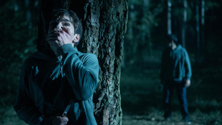 Lukas clasps his hand over his mouth while hiding from his doppelgänger 