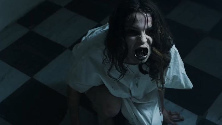 Possessed woman in white crouching on floor