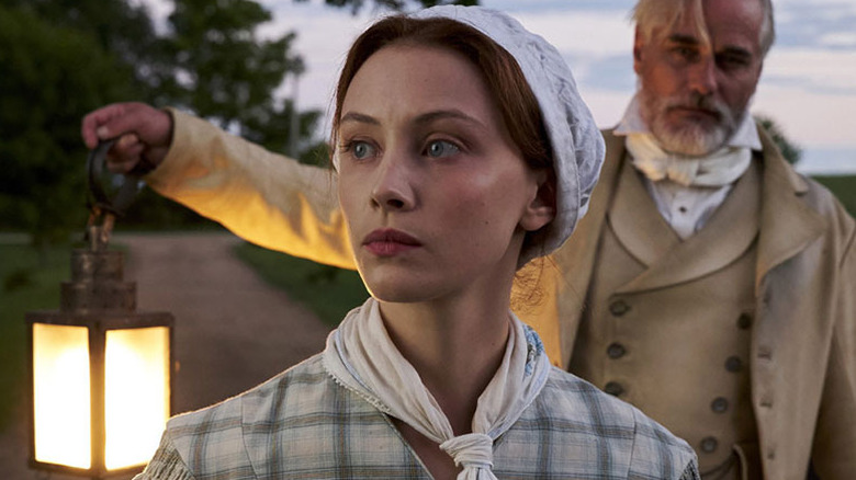 Sarah Gadon as Grace Marks, walking with Paul Gross as Thomas Kinnear, in Alias Grace