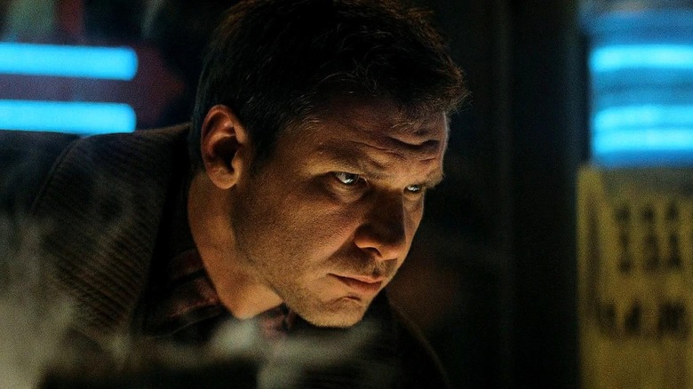 Harrison Ford as Rick Deckard in Blade Runner, leaned over and looking intently at something.