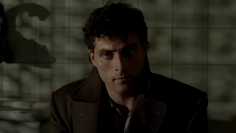 Rufus Sewell as John Murdoch, sitting in a dark room with his back against a wall.
