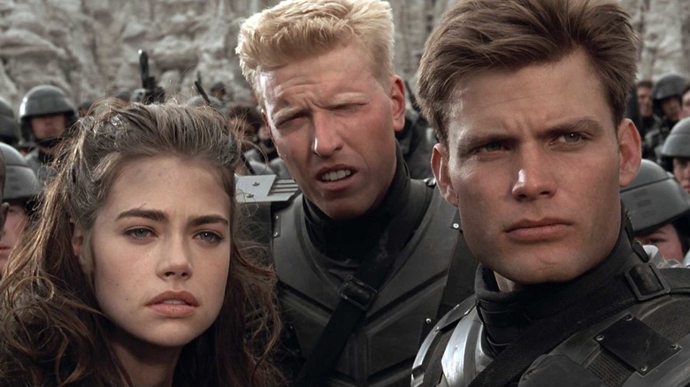 Denise Richards as Carmen Ibanez, Jake Busey as Ace Levy, and Casper Van Dien as Johnny Rico in Starship Troopers, standing among their other soldiers..