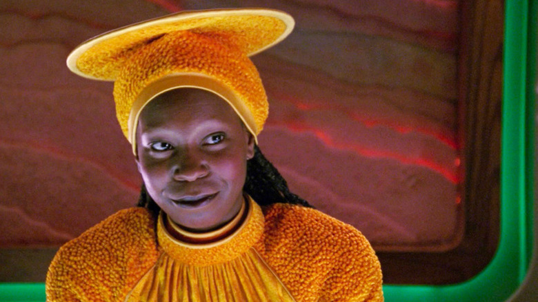 Guinan (Whoopi Goldberg) smiles while standing behind a bar in Star Trek: The Next Generation