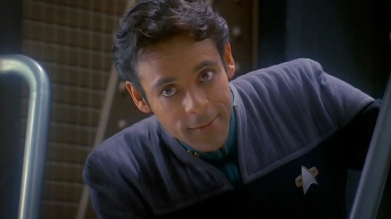 Julian Bashir (Alexander Siddig) smiles while peering down at an angle in Star Trek: Deep Space Nine