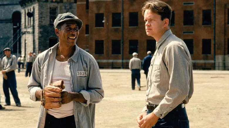 Red Reddington (Morgan Freeman) smiles while wearing a baseball mitt next to Andy Dufresne (Tim Robbins) in The Shawshank Redemption
