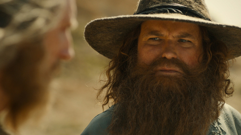 Tom Bombadil (Rory Kinnear) stares intently at the Stranger (Daniel Weyman) in The Lord of the Rings: The Rings of Power