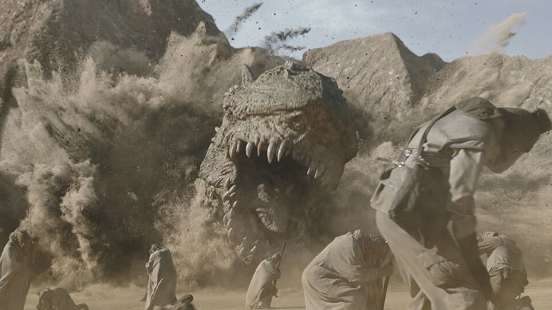 A Krayt dragon bursts roaring from the sand at a group of Tusken Raiders in The Mandalorian