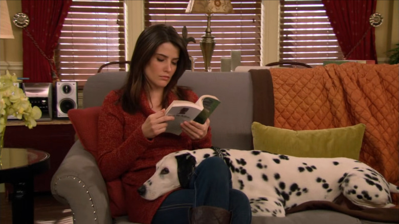 Robin Scherbatsky reading on her couch with her Dalmatian resting on her lap in How I Met Your Mother