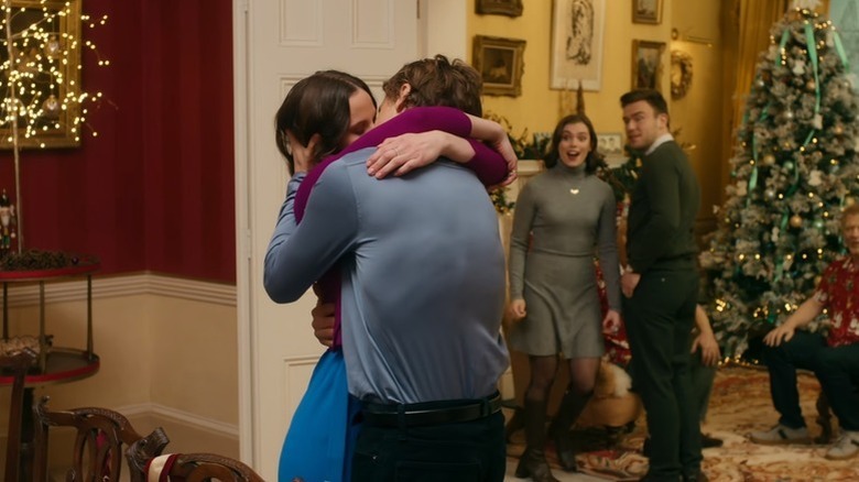 Georgia and Graham kiss in front of a Christmas tree and delighted family members in Christmas in Notting Hill