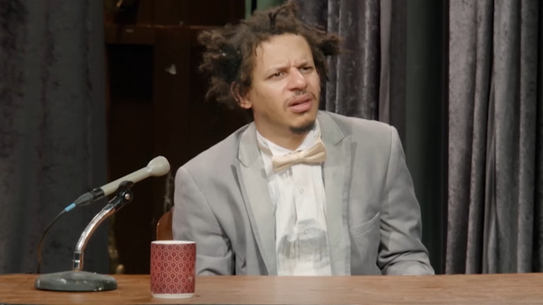 Eric Andre sitting behind his desk on The Eric Andre Show