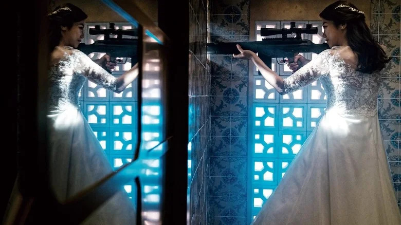 Woman in wedding dress holding rifle in front of window in The Villainess