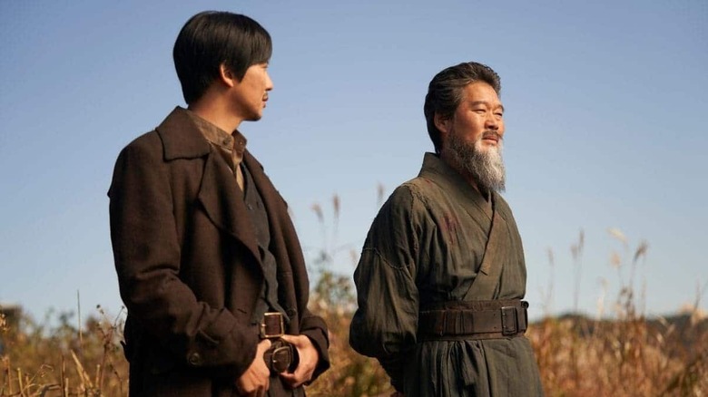 Lee Yoon (Kim Nam-gil) and Choi Chung-soo (Yoo Jae-myung) stand next to each other in a field in Song of the Bandits