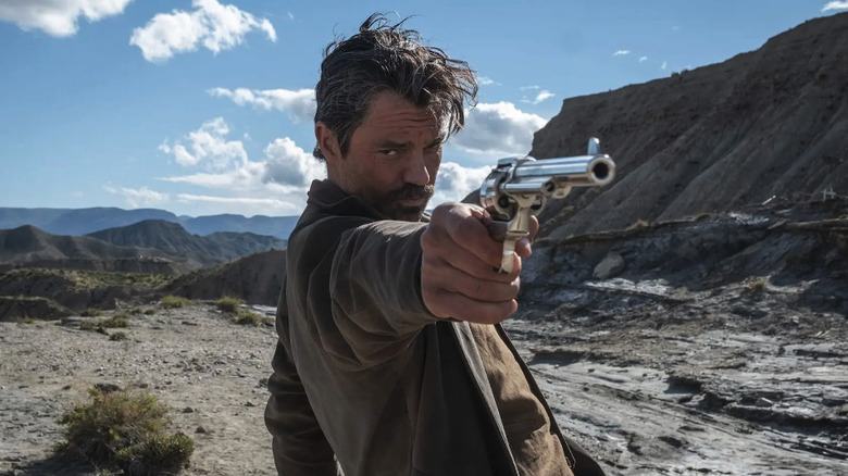 Arthur McCoy (Dominic Cooper) pointing a gun in the desert in That Dirty Black Bag