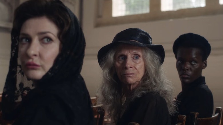 Kathy Kiera Clarke as Sybil Stamfordis, Rita Tushingham as Bella Webb, and Sheila Aatim as Thyrza Grey sitting in a church and looking over their shoulders on The Pale Horse