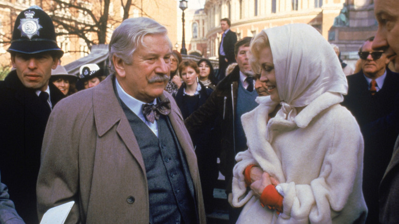 Hercule Poirot (Pester Ustinov) talking to Jane Wilkinson (Faye Dunaway) in the middle of a crowd in Thirteen at Dinner