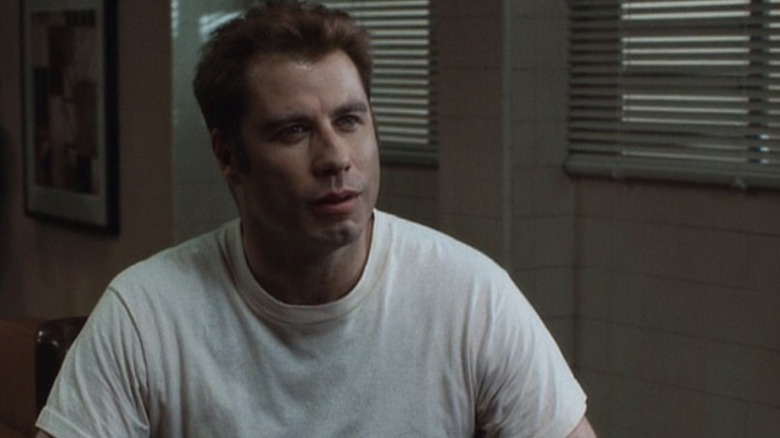 John Travolta as Louis Pinnock in White Man's Burden, sitting in a white tee shirt.