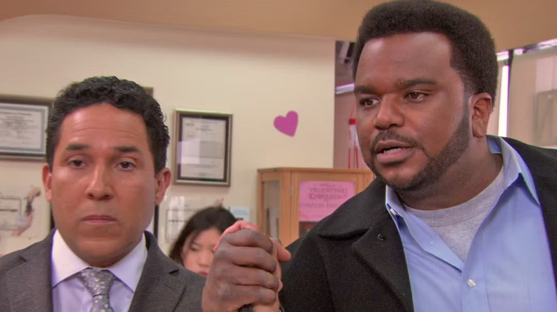 Oscar Nuñez and Craig Robinson as Oscar and Daryl, holding hands on The Office