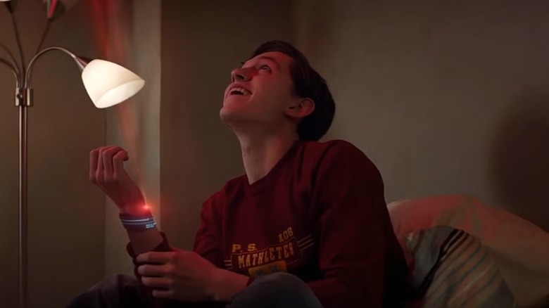 Peter Parker (Tom Holland) smiles looking up at the Spider-Man signal in Captain America: Civil War
