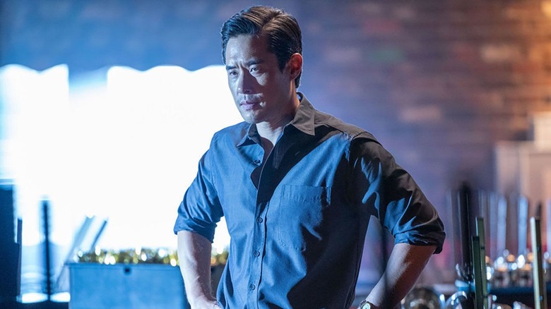 Raymond Lee as Ben Song, bathed in blue glowing light in the 2022 revival of Quantum Leap.