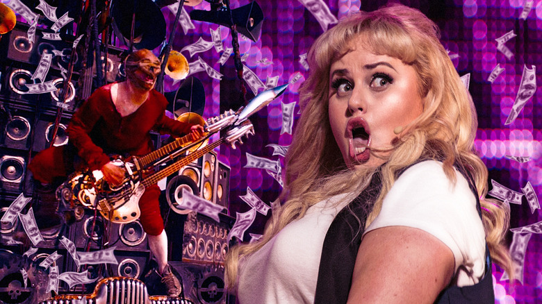 The guitar player from Mad Max: Fury Road with Rebel Wilson's Fat Amy from Pitch Perfect 2 surrounded by money