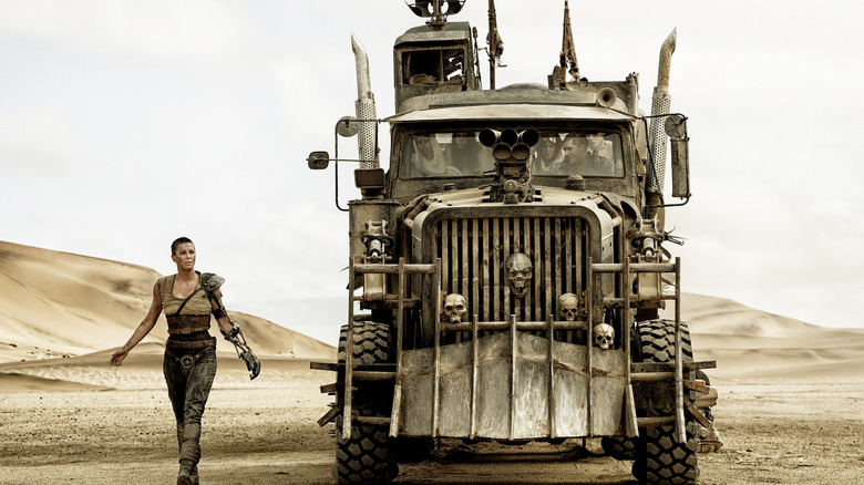 Charlizee Theron's Furiosa walking alongside the War Rig in Mad Max: Fury Road