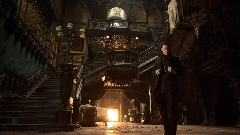 Tom Hiddleston as Thomas Sharpe standing in the entryway of the mansion in Crimson Peak