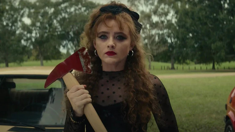 Kathryn Newton as Lisa wearing 80s-style black dress and holding bloody axe in Lisa Frankenstein