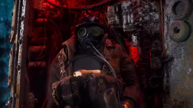 Figure in gas mask standing in front of metal object in Mad God