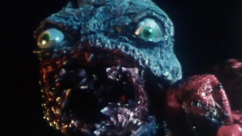 Close up of green monster creature with big eyes and red mouth in The Cat