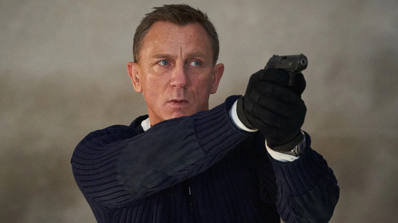 Daniel Craig as James Bond aiming a gun in No Time To Die