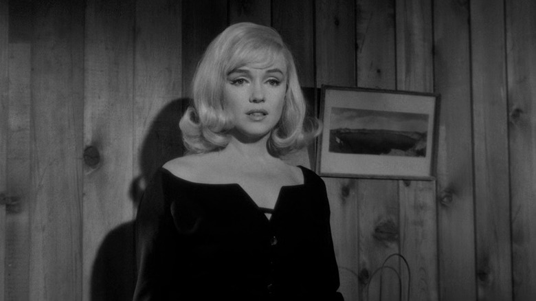 A distraught Roslyn Tabor (Marilyn Monroe) stands against a wooden wall in The Misfits