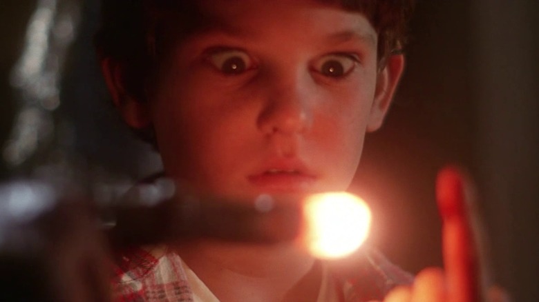 Henry Thomas as Elliott looks down at ET's glowing finger, from ET: The Extra-Terrestrial