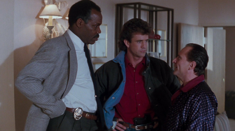 Danny Glover as Murtaugh, Mel Gibson as Riggs, and Joe Pesci as Getz, talking in Lethal Weapon 2