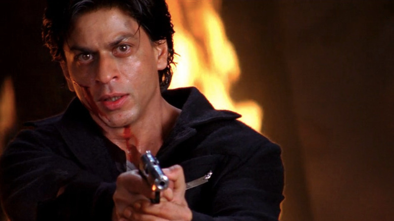 Shah Rukh Khan as O.K. pointing gun in front of fire in Om Shanti Om