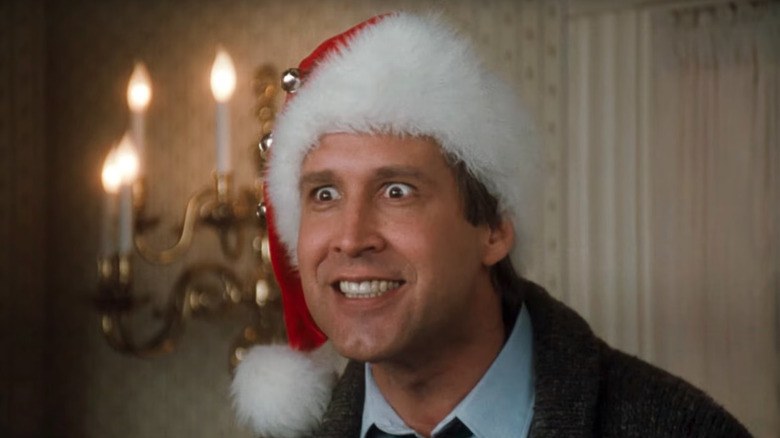 Clark Griswold (Chevy Chase) smiles with wild eyes and a Santa Claus hat in National Lampoon's Christmas Vacation