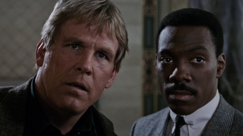 Eddie Murphy and Nick Nolte as Reggie Hammond and Jack Cates stare off-camera in 48 Hours