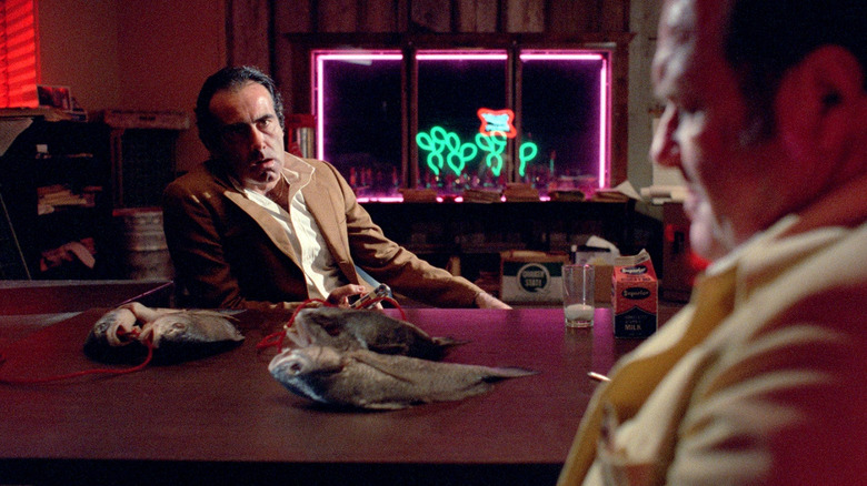 Dan Hedaya as Julian with dead fish on the table in Blood Simple