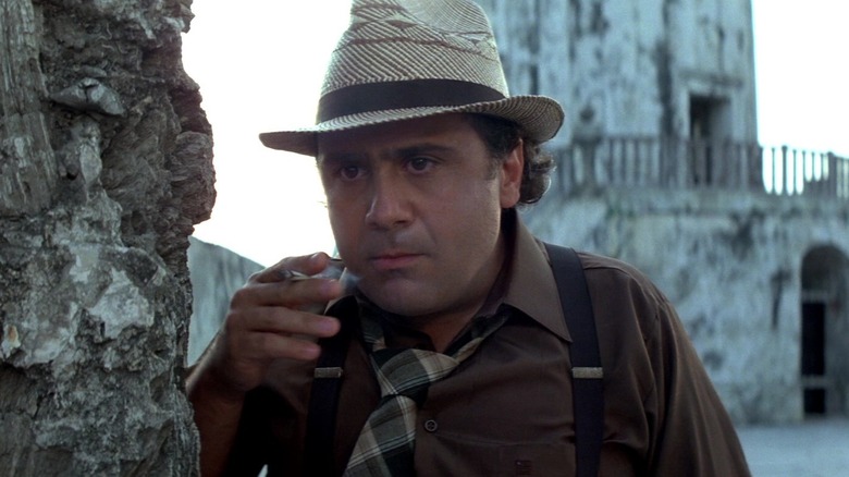 Ralph (Danny DeVito) smokes a cigarette in Romancing The Stone