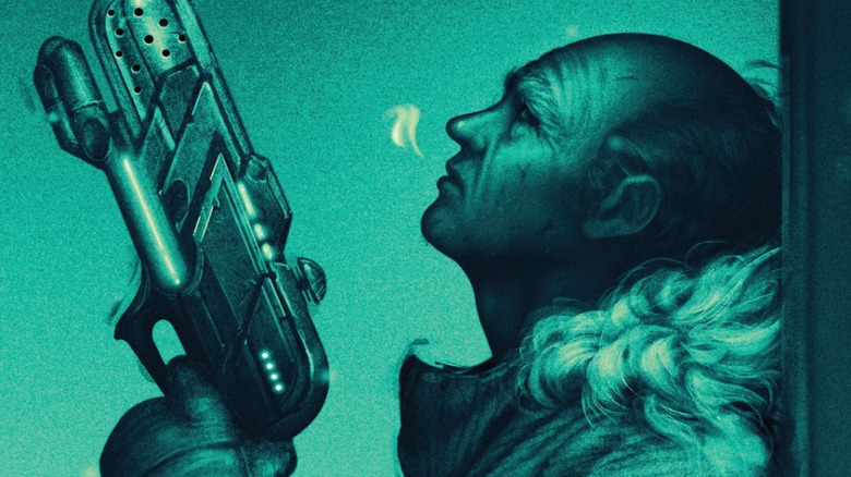 Leonard Snart leans against a wall with his gun