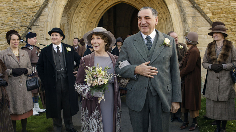 Elsie Hughes (Phyllis Logan) and Charles Carson (Jim Carter) walk out of a church arm in arm at their wedding in Downton Abbey