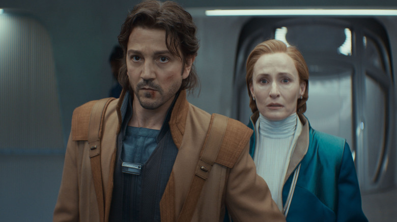 Cassian Andor (Diego Luna) leading Mon Mothma (Genevieve O'Reilly) through a hallway on Andor