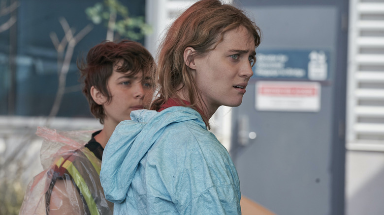 Kirsten Raymonde (Mackenzie Davis) wearing a hoodie with Alexandra (Philippine Velge) behind her on Station Eleven
