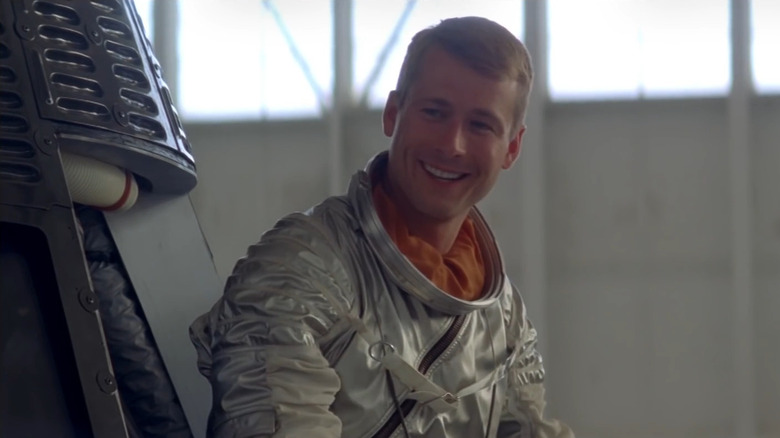 John Glenn (Glen Powell) smiling outside space capsule in Hidden Figures