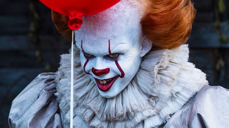 Bill Skarsgård as Pennywise, holding a red balloon in It